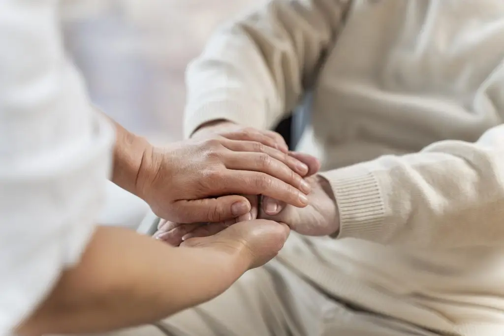 Infirmière à domicile tenant la main d'un patient âgé